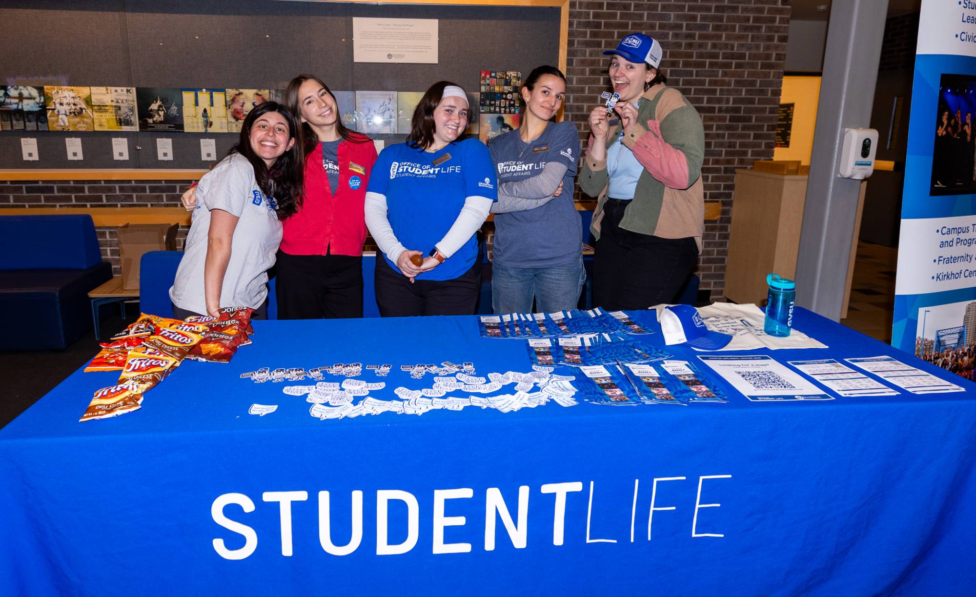 Marketing Team members smiling and standing behind the Student Life table at Campus Life Night